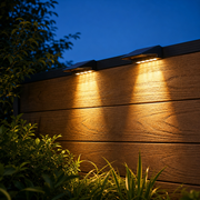 GlowHaven solar deck lights glowing warm on a cedar fence at dusk