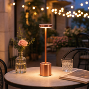 Rose gold Lumi cordless lamp on a patio table at dusk