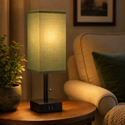 Bedside table lamp with green fabric shade in a living room reading corner