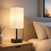 Bedside table lamp with white linen shade in a bright bedroom