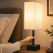 Hand pulling the pull chain on a glowing bedside lamp